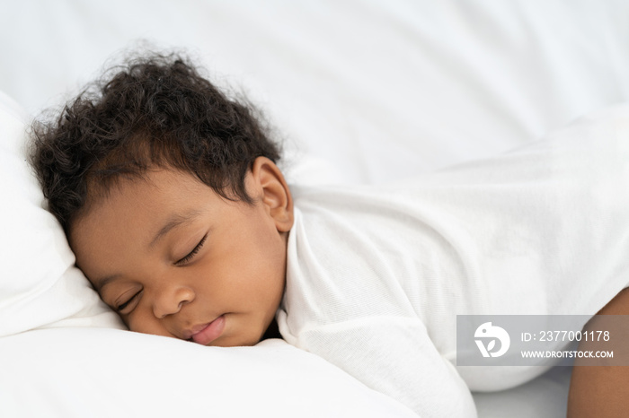 black african american baby sleeping on a white mattress.