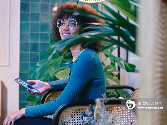 UK, London, Smiling woman looking at smart phone in modern office