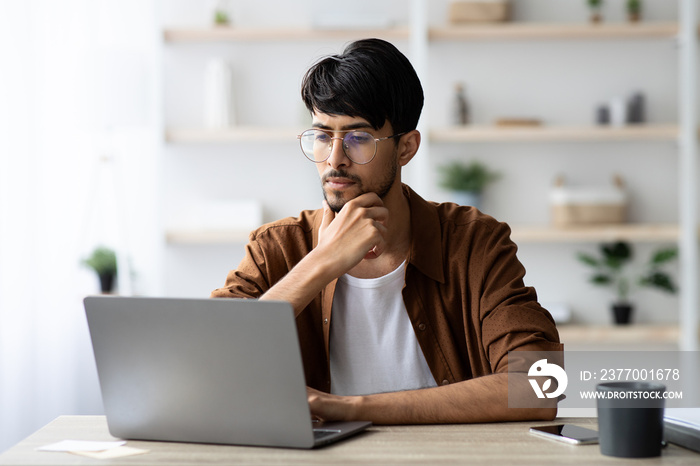 Pensive arabic man employee working on modern notebook