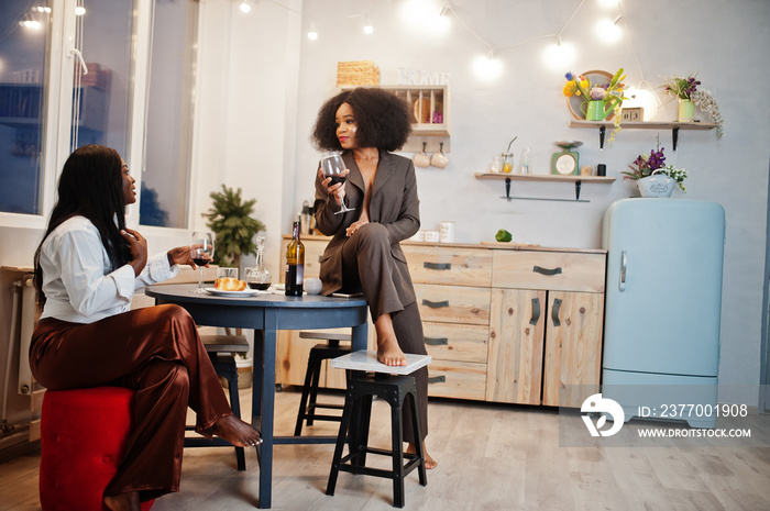 Two african american female friends women spending time at kitchen with wine. Black girlfriends  relaxing at home.