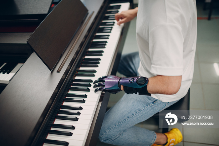 Young disabled man play on piano electronic synthesizer with artificial prosthetic hand in music shop