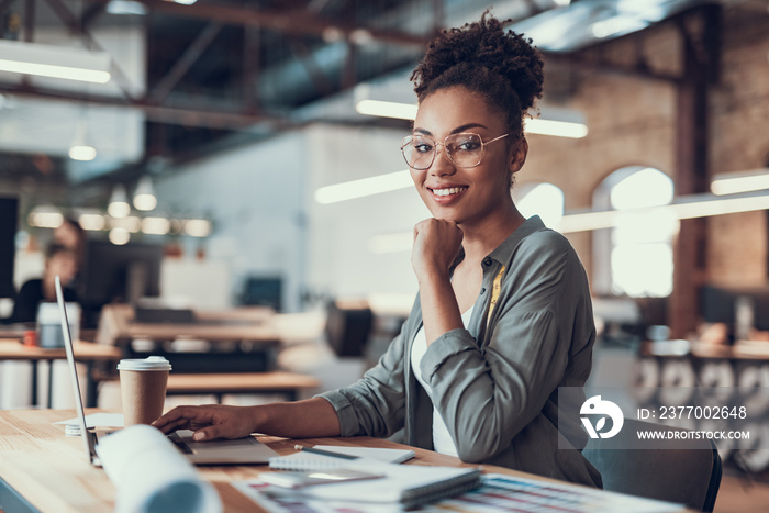 Charming afro american girl working on laptop at modern office