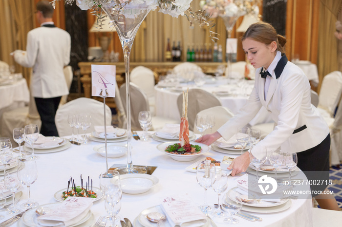 Waiters set the tables in the restaurant for the banquet