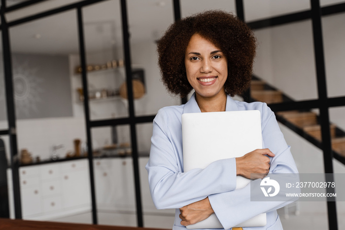 Confident african woman realtor with laptop showing apartments for rent or purchase. Mortgage for flat for clients. Creative photo for real estate agency.