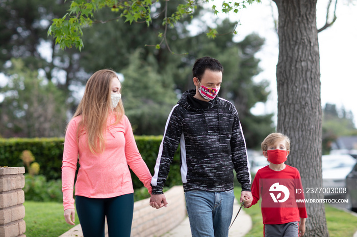 A family walking holding hands wearing face masks in the middle of pandemic