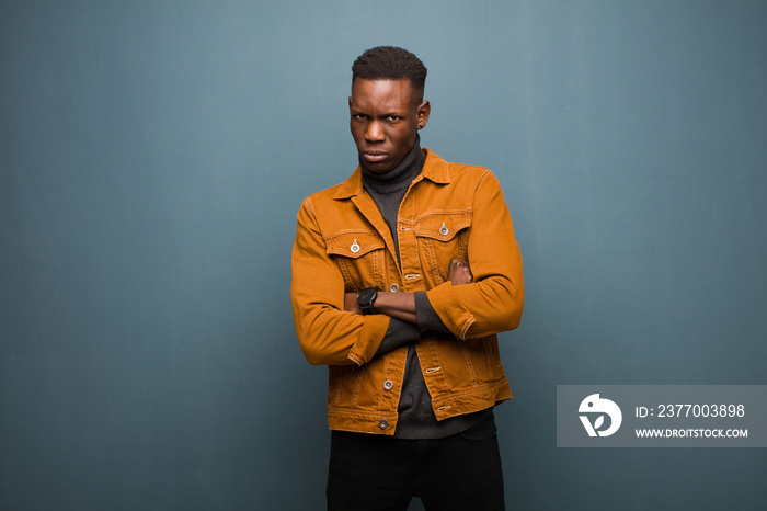 young african american black man feeling displeased and disappointed, looking serious, annoyed and angry with crossed arms against grunge wall