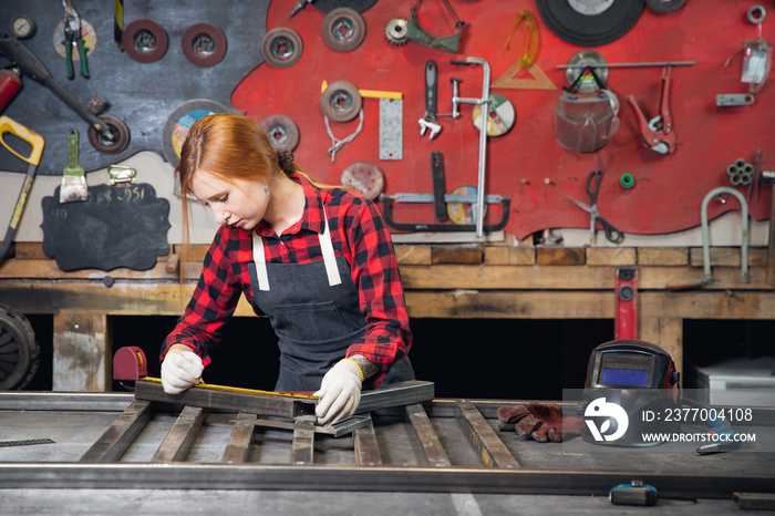 Portrait beautiful woman welder background industry factory workplace. Manufacture of metal structures, measures size of ruler