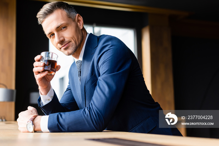 businessman in suit holding glass and looking at camera