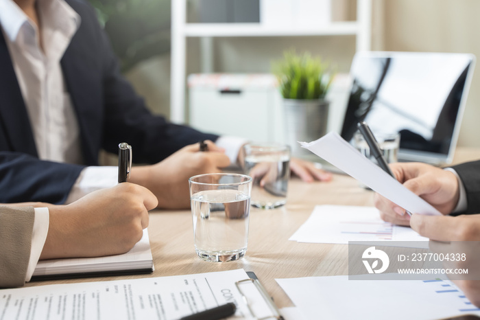 Close up hands of a businessman holding graph paperwork on the meeting conference table.