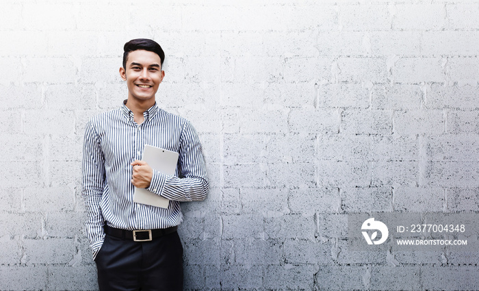 Happy Friendly Young Businessman standing at the Wall, Smile and holding a Digital Tablet, Lifestyle of modern male. Looking at camera