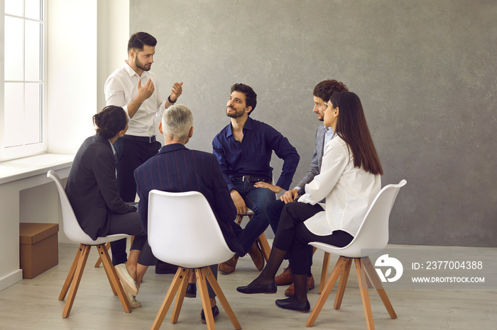 Entrepreneurs having a discussion. Experienced business coach talking to group of people. Young manager sharing ideas, opinions and points of view trying to convince teammates to follow his suggestion