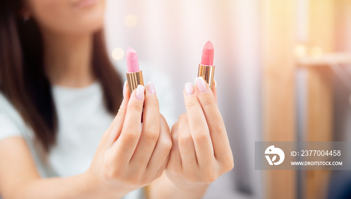 Woman is choosing new lipstick applies colour on skin of hand