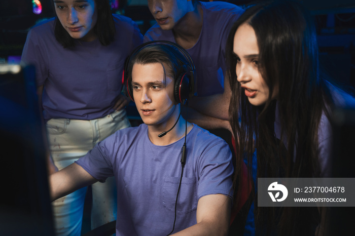 Boy playing in a computer club, while his friends standing behind and prompting