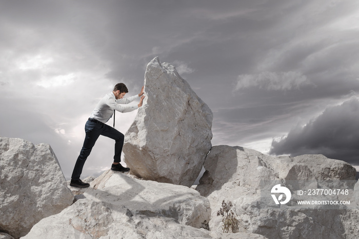 Business concept, Young businessman pushing large stone uphill with copy space