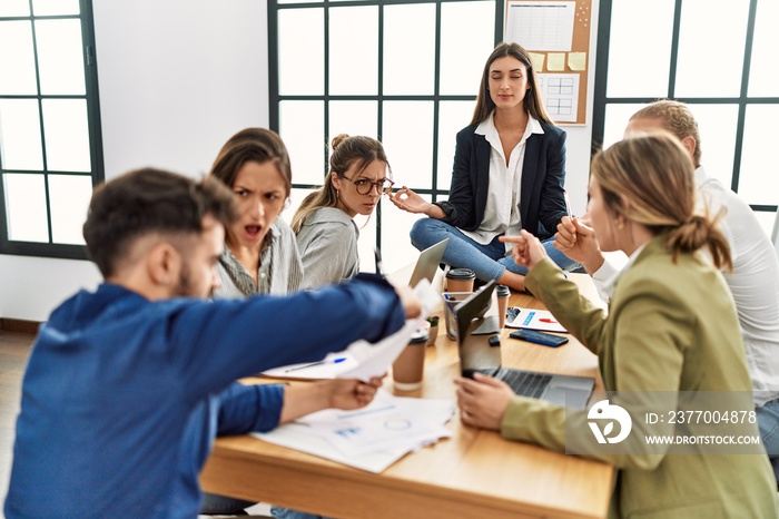 Businesswoman enjoys meditating during meeting. Sitting on desk near arguing partners at the office.