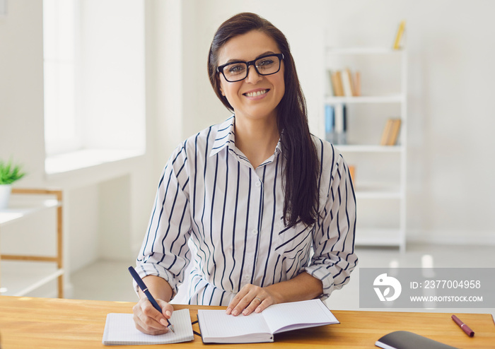 Hispanic teacher with glasses looking at the camera smiling. A college university teacher teaches remotely using a video call application gadget.