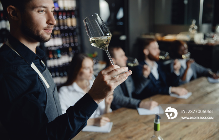 Professional sommelier conducts white wine tasting for business company in restaurant