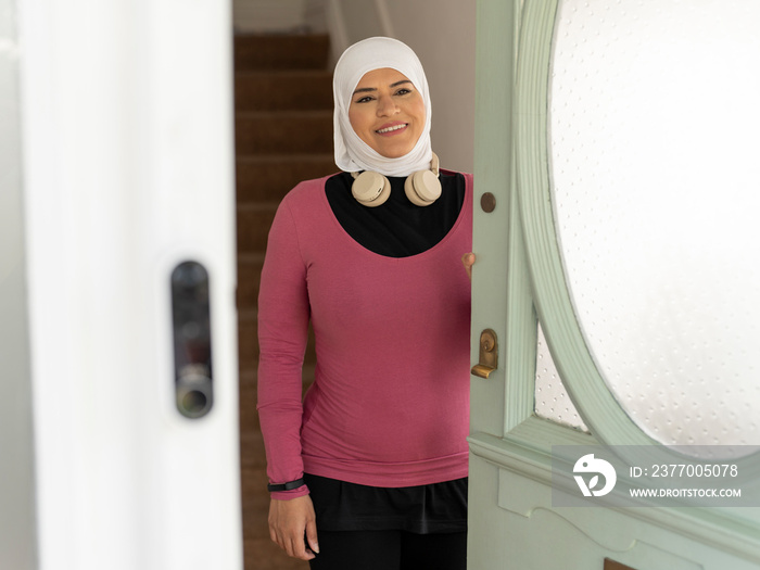 UK,Sutton,Smiling woman in headscarf and sports clothing leaving house