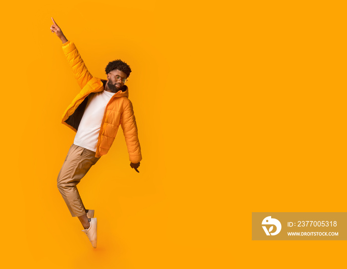 Joyful back man in winter clothes posing over orange background