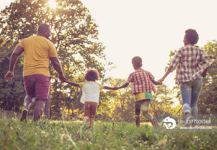 African American family having fun outdoors. Family running trough park.