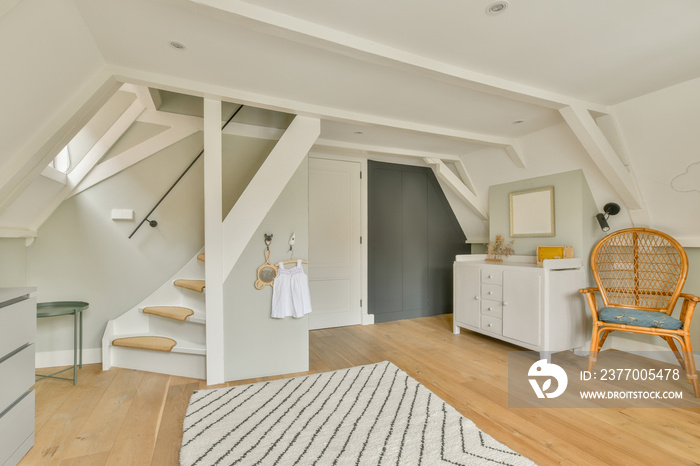 Interior of white room with baby crib and armchair near window with chest of drawers in daylight