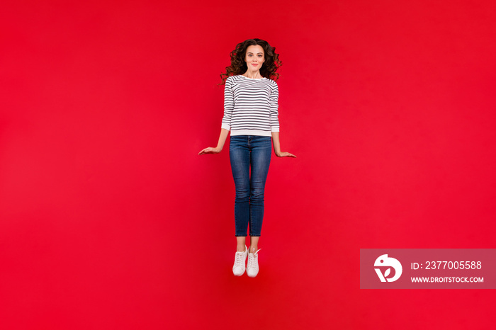 Full length size body photo of attractive she her girl with amazing wave hair jump in air wearing white casual sweater denim jeans isolated on red vivid bright background