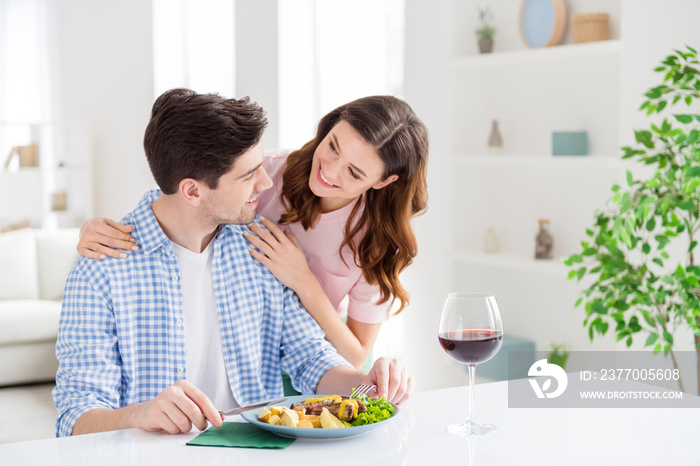 Portrait of two nice attractive careful lovely sweet adorable cheerful cheery spouses enjoying eating tasty yummy meal embracing staying home in light white interior kitchen house apartment