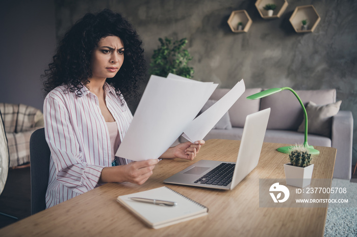 Photo portrait of confused woman holding papers comparing trying to understand indoors