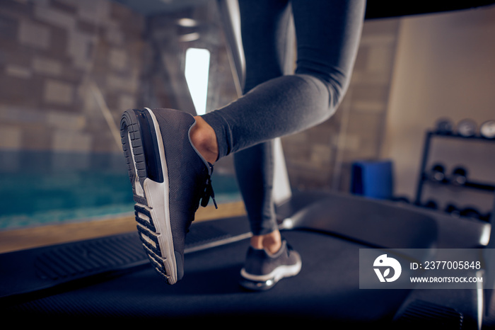 Close up of woman’s legs running on treadmill. Gym interior.