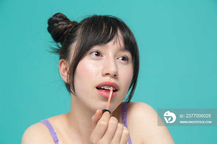 Studio portrait of girl applying lip gloss