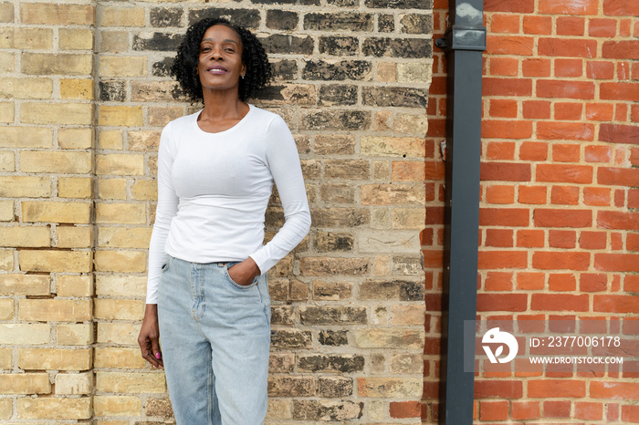 Portrait of smiling woman standing by brick wall