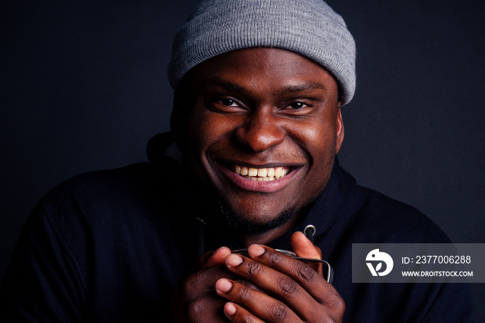 happy portrait of afro male holding metal tourist thermos mug with snow-white good feeling smile.tourist wearing gray hat and black hoody studio black background