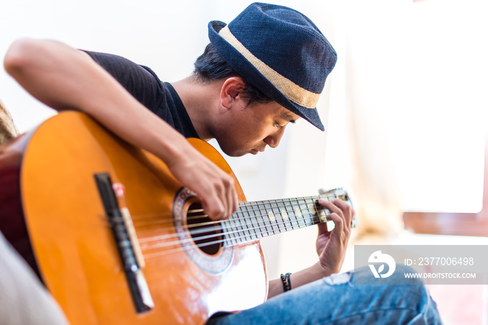 Young Asian Guy Playing Guitar at Home.  Man Playing Guitar in his House.