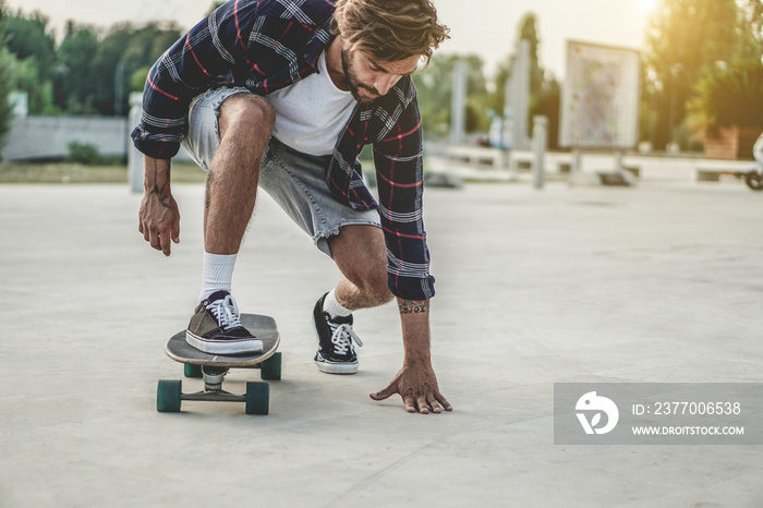 Tattoo skater performing with longboard at sunset in urban city square