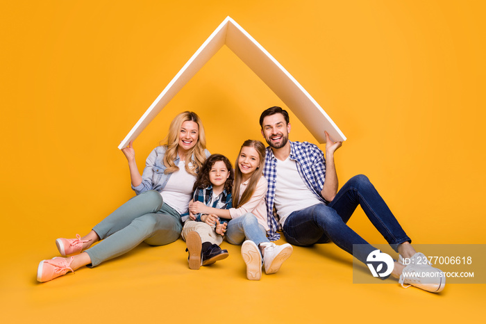 Photo offspring mommy daddy daughter small son happy together four member family support care hold hands roof above their head moving big dream house isolated yellow color background