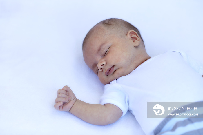 Newborn baby boy sleeping on back on a white blanket