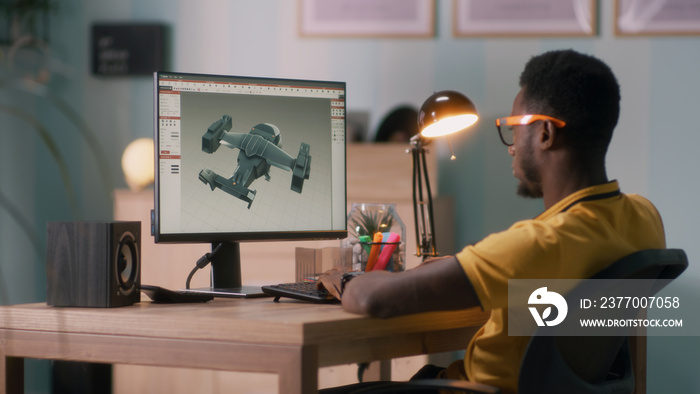 African American man in glasses using computer to create 3D model of aircraft while working at home office