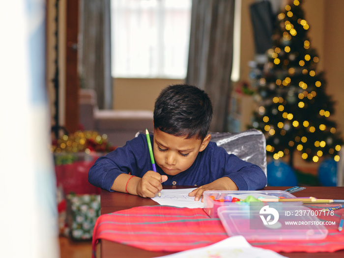 Boy sitting at table and drawing during Christmas