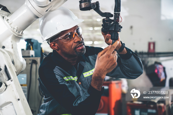 African American factory worker working with adept robotic arm in a workshop . Industry robot programming software for automated manufacturing technology .