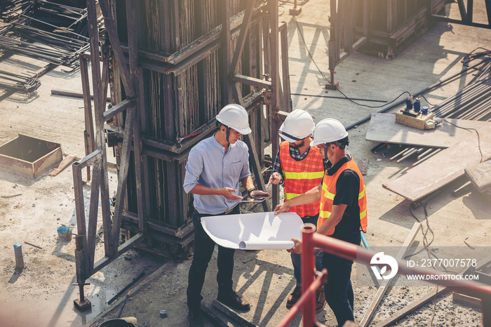 Structural engineer and foreman worker with blueprints discuss, plan working for the outdoors building construction site.