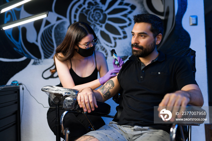 Handsome man getting an arm tattoo