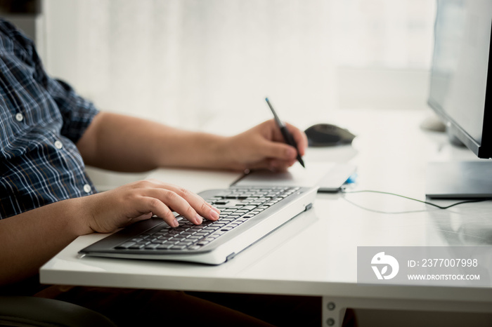 Toned photo of graphic designer using tablet and keyboard at wor