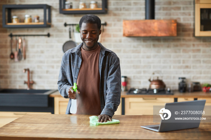 Portrait of smiling African-American man enjoying spring cleaning in modern home interior, copy space