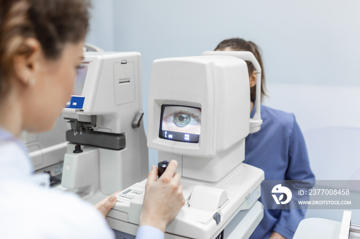 Doctor testing for eyes with special optical apparatus in modern clinic. Ophthalmologist examining eyes of a patient using digital microscope during a medical examination in the ophthalmologic office