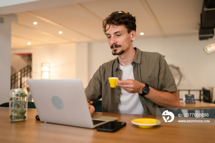 One young adult caucasian man work remote from cafe on laptop computer