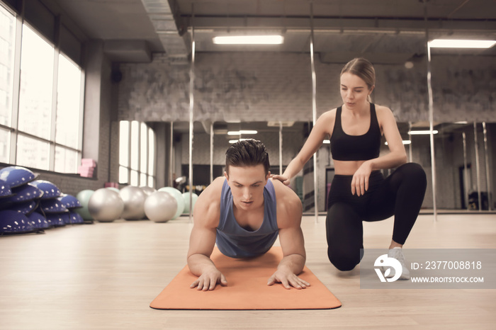 Young man training with coach in modern gym