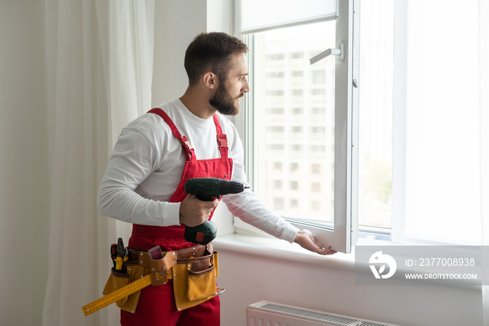 handsome young man installing bay window in a new house construction site.