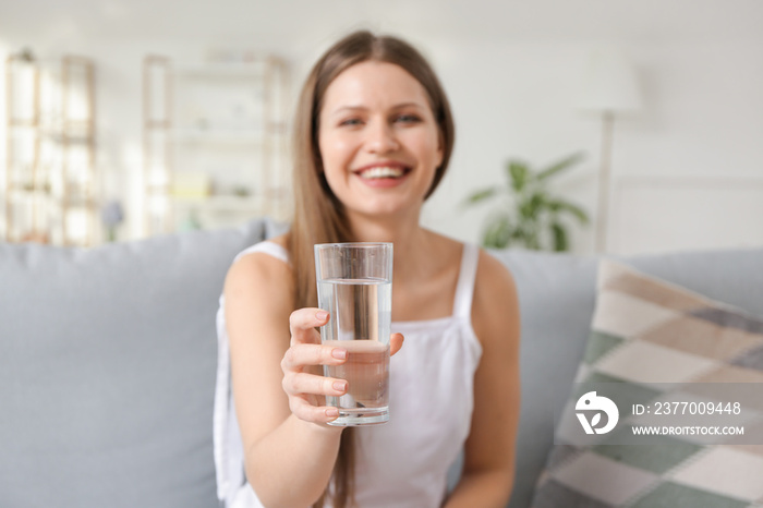 Beautiful young woman drinking water at home