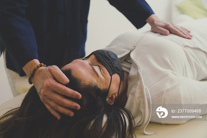 Therapist man doing Holistic therapy Reiki to a woman. Energy treatment with the heat of the palm hands. Japanese energy healing. Wellness, health, relax, well-being and alternative medicine concept.