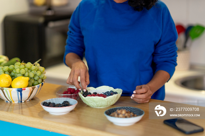 Brunette woman making a healthy yogurt and fruit breakfast.